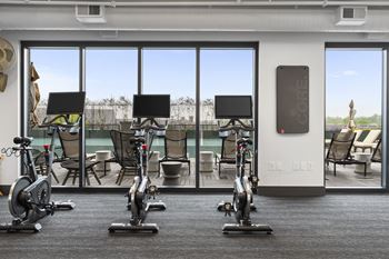 a gym with exercise machines and a view of a pool at Deca Apartments, Greenville, SC